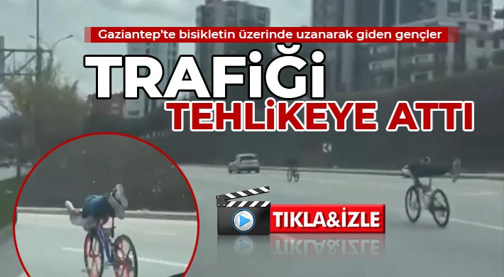Bisikletin üzerinde uzanarak giden gençler trafiği tehlikeye attı