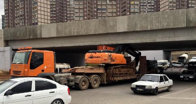 TIR, üstündeki iş makinesi ile köprüye takıldı